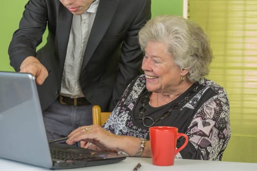 Elderly lady and young man working together on the laptop.