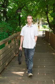 Young man walks purposefully over a bridge