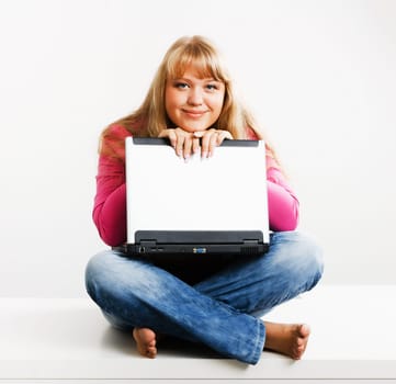 smiling blond girl with a laptop sitting on the table
