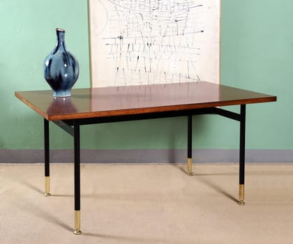 Blue vase on wooden table with white board plans in background, modern room