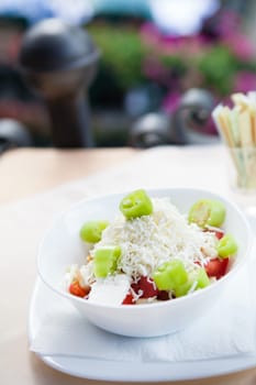 Closeup of healthy green and red chili salad with grated cheese in white bowl