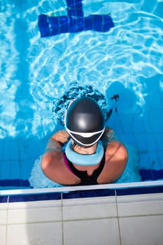 Female freediver with neck weight and monofin at edge of outdoor swimming pool