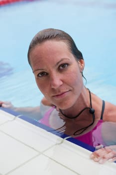 Female swimmer resting at edge of outdoor swimming pool