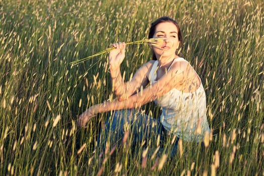 Outdoor portrait of a beautiful woman smelling flowers on a summer day