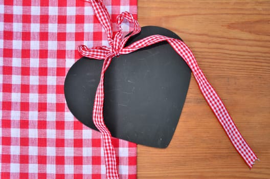 a black heart red rarized bow on wooden background