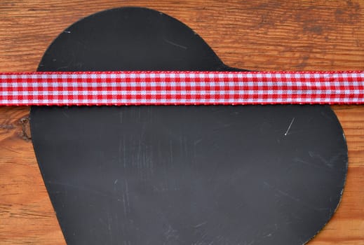 a black heart red rarized bow on wooden background