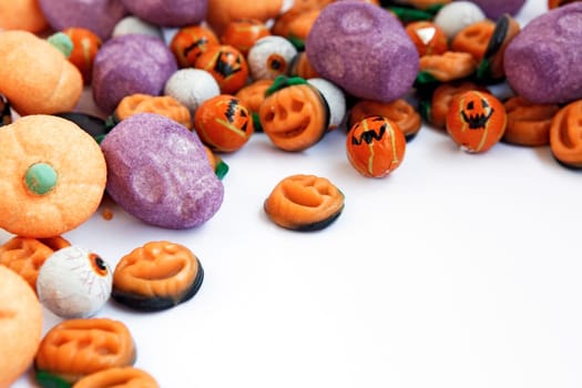 Colorful group of halloween candy in shape of pumpkins and skulls with funny, smiley faces. Large space for copy.