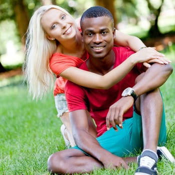 Young in love multicultural couple on a meadow in summer leisure fun