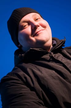 Upper body portrait of a middle-aged man in a black jacket in the evening against a blue sky in soffit