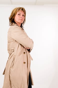 side three-quarter view of a middle-aged woman in front of a white background with folded arms arrogantly looking into the camera