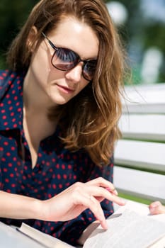 Young woman lying on bench and turn page