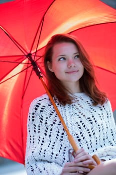 Happy young woman with open umbrella at hand