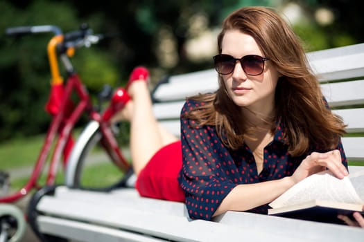 Young woman lying on bench and notise something