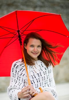 Smiling young woman with open umbrella at hand