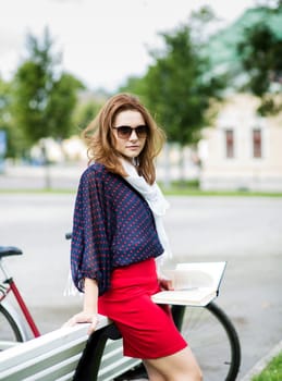 Young woman rests on bench and hold book
