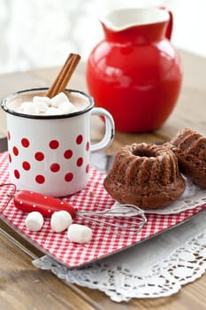 Hot chocolate in vintage cup with small chocolate cake and marshmallows