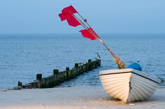 small white fishing boat with red flagged buoys on the Baltic Sea beach near the town of Heringsdorf in summer 2013