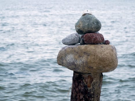 Natural stones stacked on top of each other on wooden posts in front of North Sea water surface