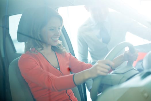 Photo of smiling woman sitting in car with salesman near by