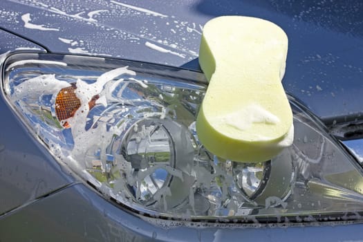Car wash. Sponge with foam on the car-lights