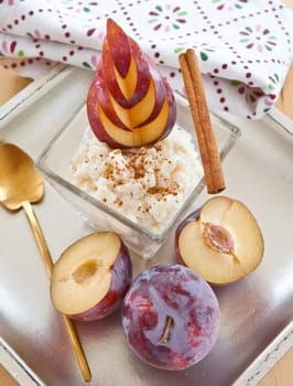rice pudding in small bowls with cinnamon and fresh plums