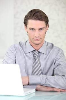 Man wearing shirt and tie sat with laptop
