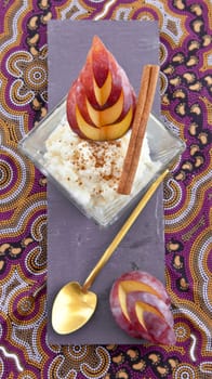 rice pudding in small bowls with cinnamon and fresh plums