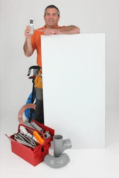 Plumber with mobile stood by poster