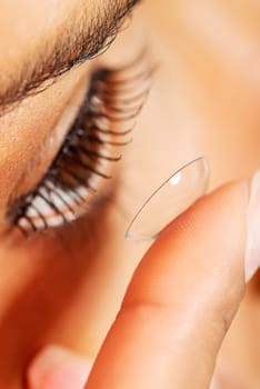 Close up of a woman putting contact lens in her eye