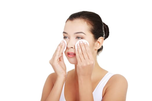 Portrait of happy young woman cleaning skin by cotton pad, over white background