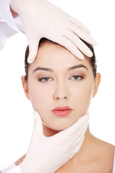Plastic surgery concept. Doctor hands in gloves touching the beautiful woman face. Isolated on white