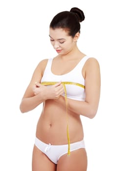 Pretty smiling woman measuring breast with measurement type - isolated on white