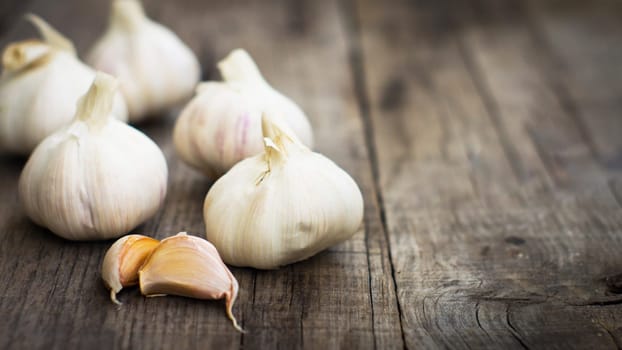 Several fresh garlic cloves on wood background.