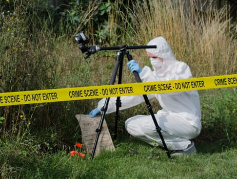 Forensic scientist checking for evidence behind a crime scene barrier