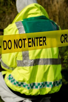 Police officer working behind a crime scene barrier