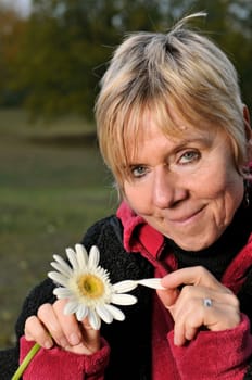 elderly woman plucks petals of a flower