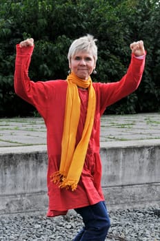 elderly woman in red robe in victory pose  mature woman in red with winner pose