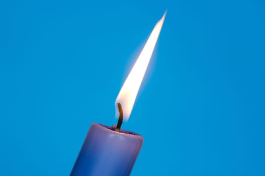Flame of blue candle on the blue background