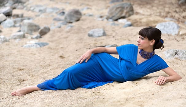 girl in a blue dress lying on the sand