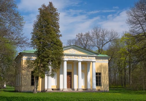 Old house with columns in the woods on a background of blue sky with clouds