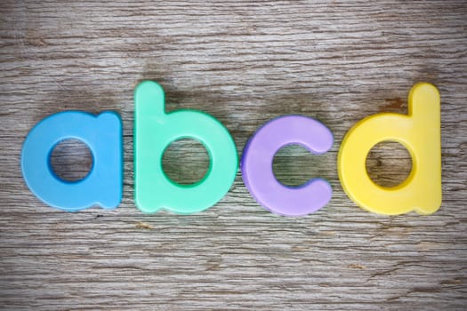 Letter magnets "ABCD"" close up on wood background"