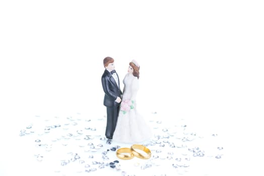Pure gold wedding rings with bride and groom figurine background