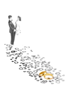 Pure gold wedding rings with hearts ornament and wedding couple at the background