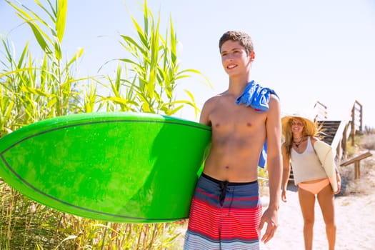 Teenager surfers walking to the beach in sunny summer day
