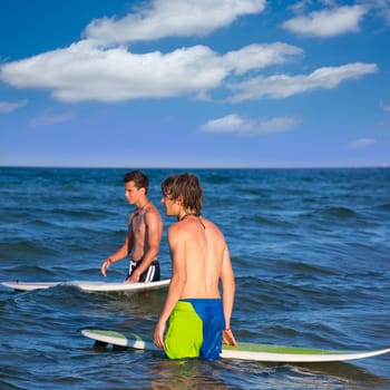 boys surfers waiting for the waves on the blue beach