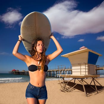 Brunette surfer teen girl holding surfboard in Huntinton Beach California