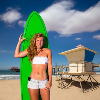 Blond surfer teen girl holding surfboard in Huntinton Beach pier California
