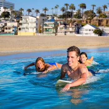 Teenager surfer group boys and girls swimming over the surfboard in santa monica california