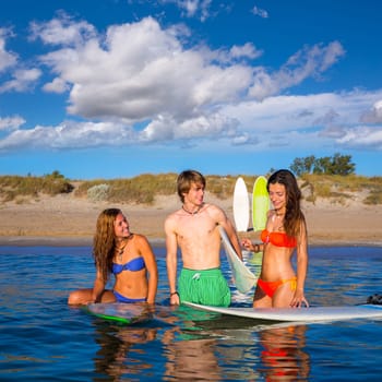 Happy beautiful teen surfers talking on beach shore smiling