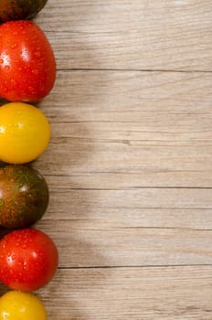 Old wood with tomatoes in red,yellow and green as edge